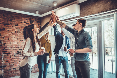 Successful business team is giving high five and smiling while standing in office