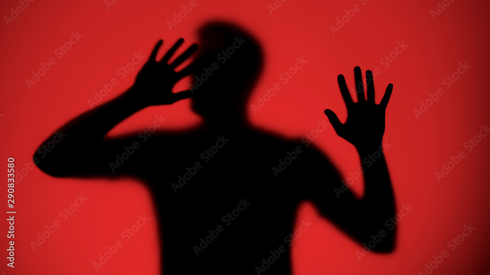 Desperate male silhouette trying to escape from captivity, red background