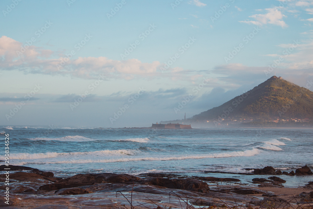 Mountain on ocean coast in the morning. Scenic landscape near Caminha, Portugal. Panoramic seascape with stones in water and green hill on horizon. Camino de Santiago landscape. 