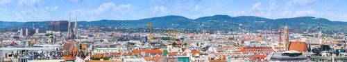 Aerial panoramic cityscape view of austrian capital city of Vienna. Summertime sunshine day, small cumulus clouds in the blue sky.