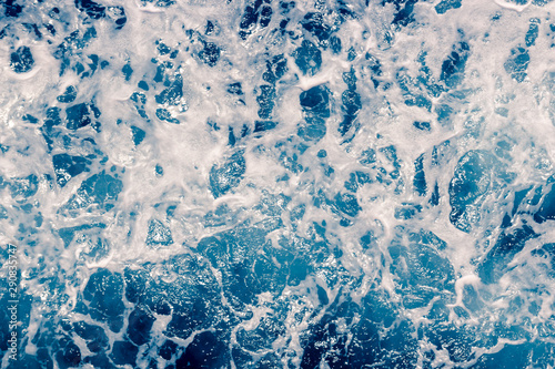 Pale blue sea surface with waves and foam, abstract background
