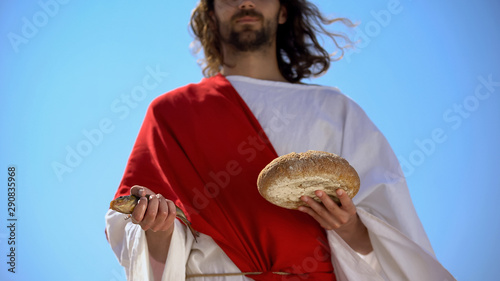 Fotografía Man in robe holding fish and bread, charity concept to feed hungry, generosity