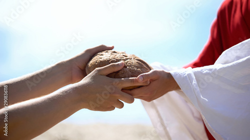 Jesus hands giving bread to poor man, biblical story to feed hungry, charity photo