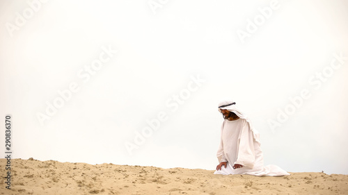 Canvas-taulu Tired Bedouin kneeling in desert, exhausted and lost, overcoming difficulties