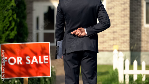 Inexperienced broker crossing fingers behind his back before selling house, luck