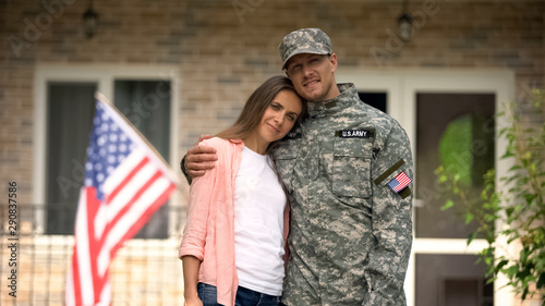 Former soldier and girlfriend hugging, standing against USA flag, homecoming
