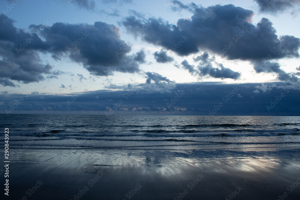 Low tide sea with clouds and reflection on sand