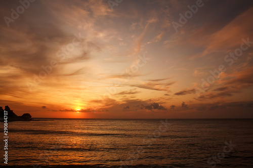 Colorful sunset over the sea coast on sky and clouds background