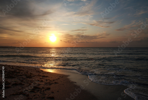 Colorful sunset over the sea coast on sky and clouds background