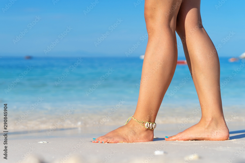 Girl standing barefoot on the sand beach female feel walking in summer vacation sunny day by the sea or ocean