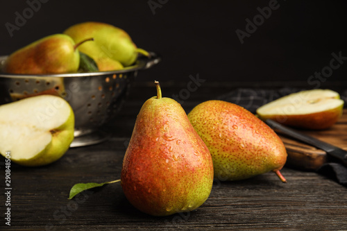 Fotografie Ripe juicy pears on dark wooden table against black background