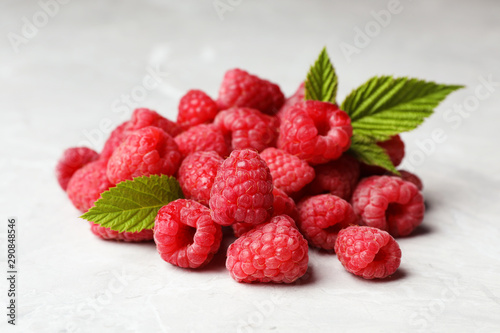 Heap of delicious ripe raspberries on light marble background, closeup