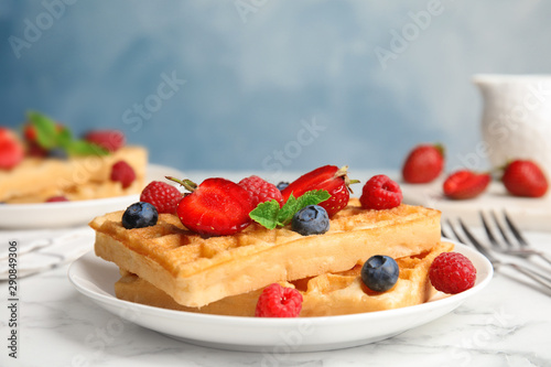 Delicious waffles with fresh berries served on white marble table
