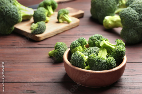 Bowl of fresh green broccoli on wooden table, space for text