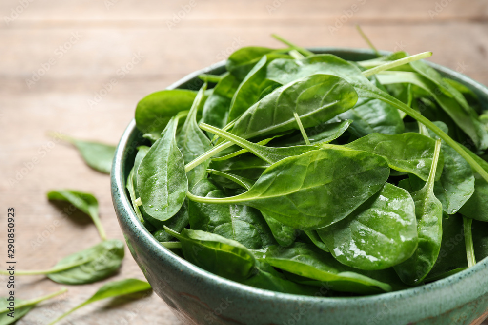 Bowl of fresh green healthy spinach on wooden table, closeup Bowl of fresh green healthy spinach on wooden table, closeup