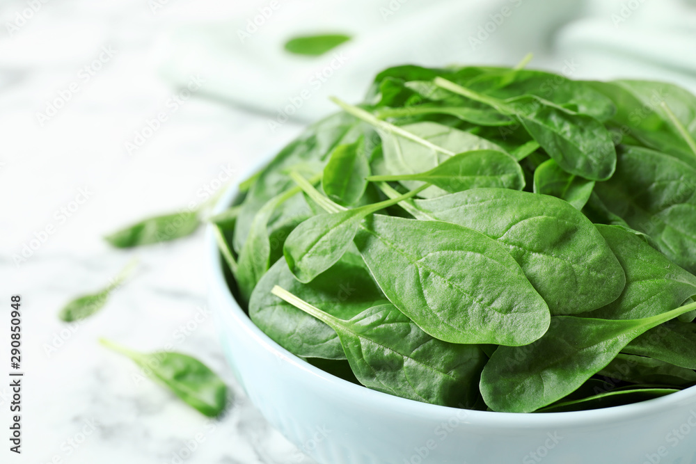 Bowl of fresh green healthy spinach on white marble table, closeup Bowl of fresh green healthy spinach on white marble table, closeup