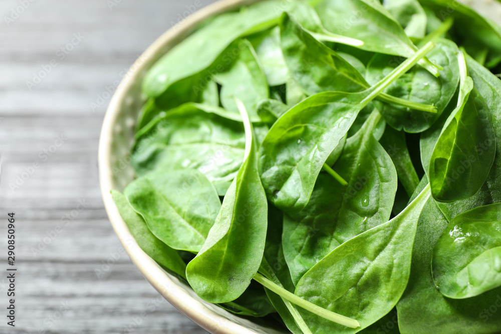 Bowl of fresh green healthy spinach on dark wooden table, closeup Bowl of fresh green healthy spinach on dark wooden table, closeup