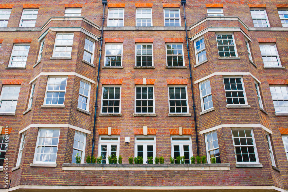 Facade of anonymous English British apartments residential building in red bricks
