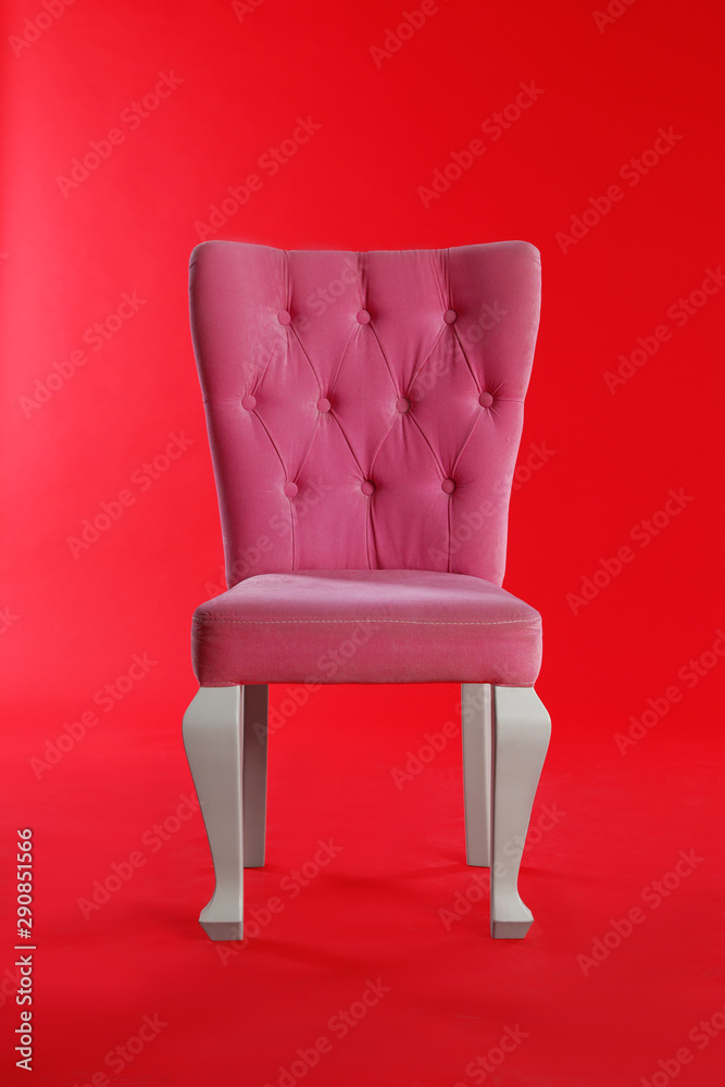 Stylish pink chair on red background. Element of interior design Stylish pink chair on red background. Element of interior design