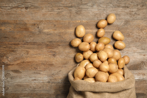 Raw fresh organic potatoes on wooden background  top view. Space for text