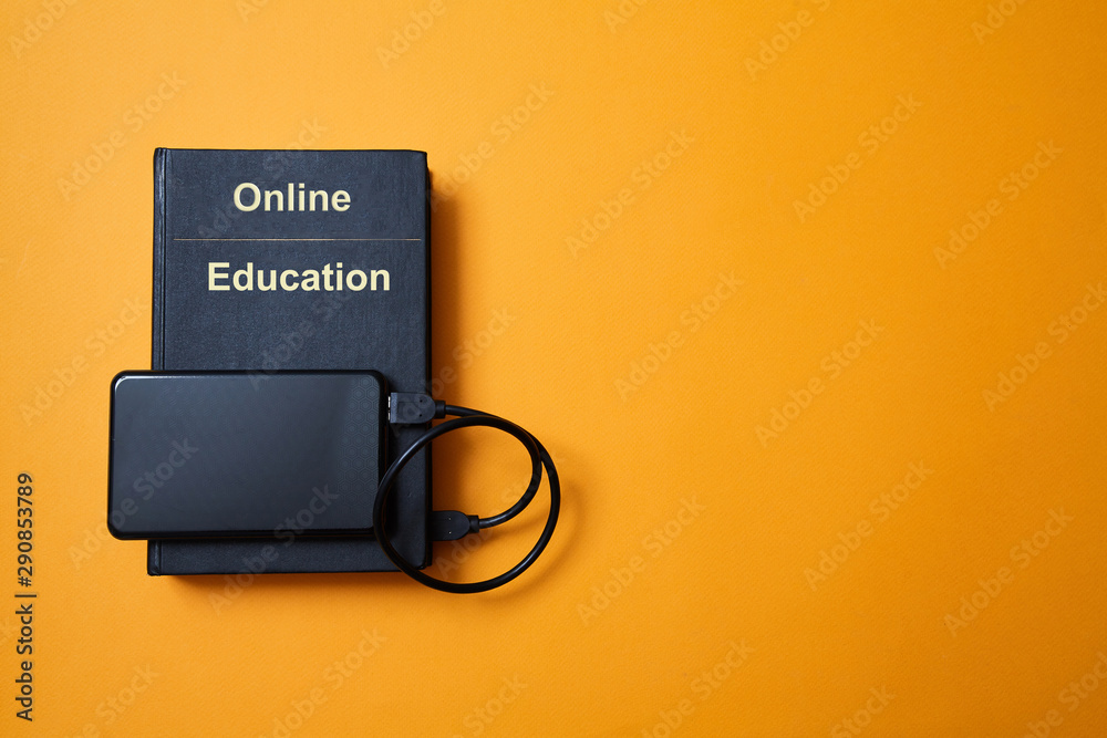 E-library. E-learning, online education or e-book. Webinar, internet courses. Book and hard drive on yellow background E-library. E-learning, online education or e-book. Webinar, internet courses. Book and hard drive on yellow background