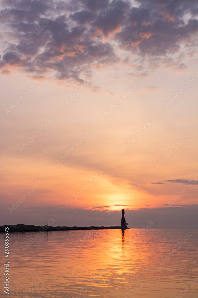 sunset over the sea with lighthouse and clouds