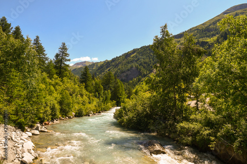 Scenic view of the Doire de Ferret, a tributary of the Dora Baltea River, that flows in Val Ferret among rocks and pine forests at the foot of Mont Blanc massif in summer, Courmayeur, Aosta, Italy
