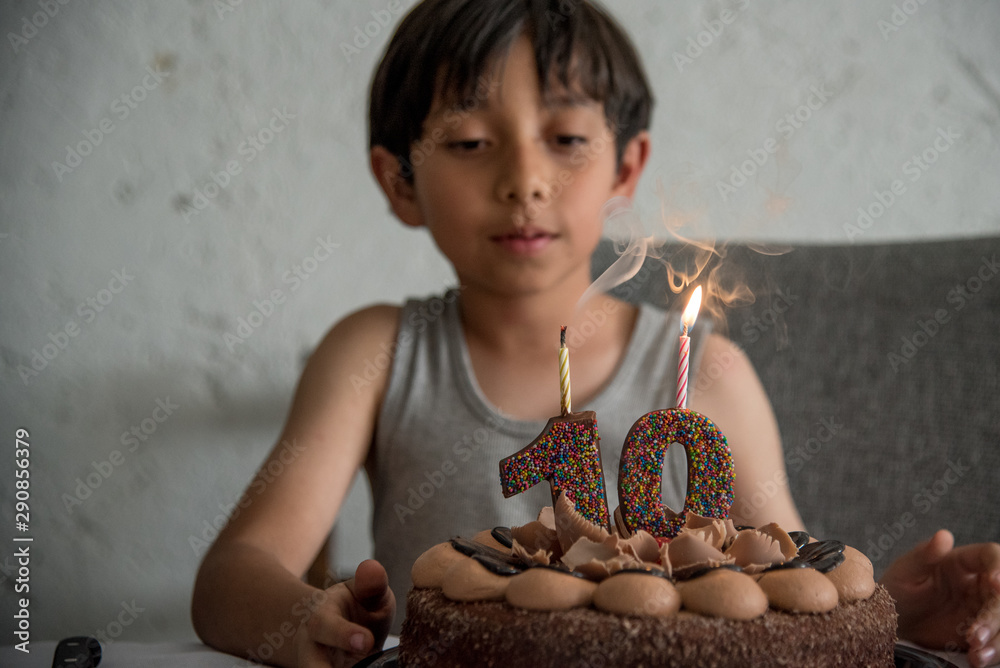  niño celebrando el cumpleaños numero   con pastel y velas de aniversario, soplando al pastel foto de Stock