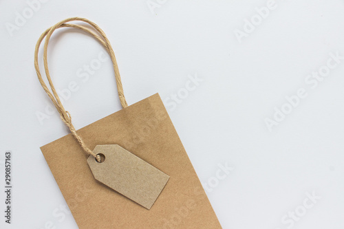 Blank mockup kraft paper present shopping bag with label tag on white background. Photo with copy blank space on the right of image.