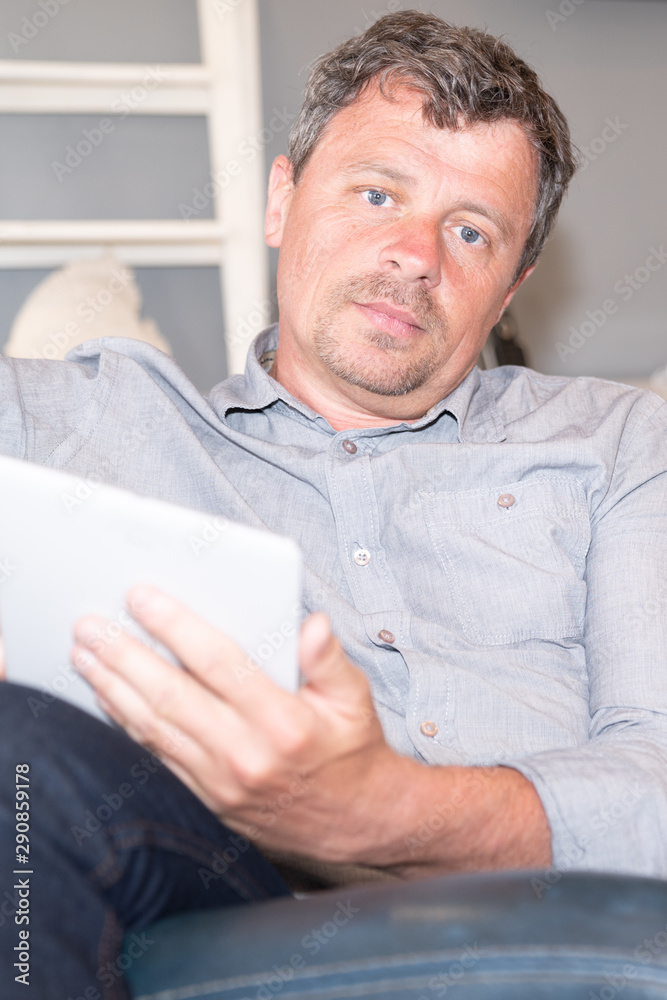 Handsome man at home relaxing in sofa with tablet Handsome man at home relaxing in sofa with tablet