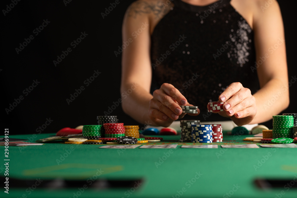 a girl in an evening dress plays poker by raising bets with chips in a casino. focus on chips in focus a girl in an evening dress plays poker by raising bets with chips in a casino. focus on chips in focus