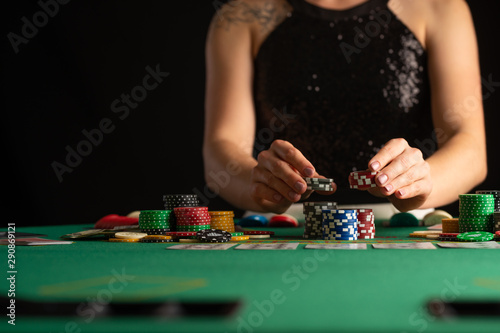 a girl in an evening dress plays poker by raising bets with chips in a casino. focus on chips in focus