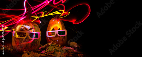 luminous pumpkins in the dark for the autumn Halloween holiday. 3D movie for Halloween. Pumpkin Head Jack in 3D glasses for the movie. Bright neon pink and blue light in the darkness of Freezelight