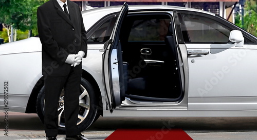 Limo driver standing next to opened car door with red carpet © noraismail
