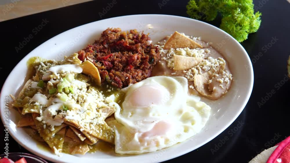 rich traditional breakfast with fried eggs, beans, nachos chilaquiles, meat gratin rich traditional breakfast with fried eggs, beans, nachos chilaquiles, meat gratin