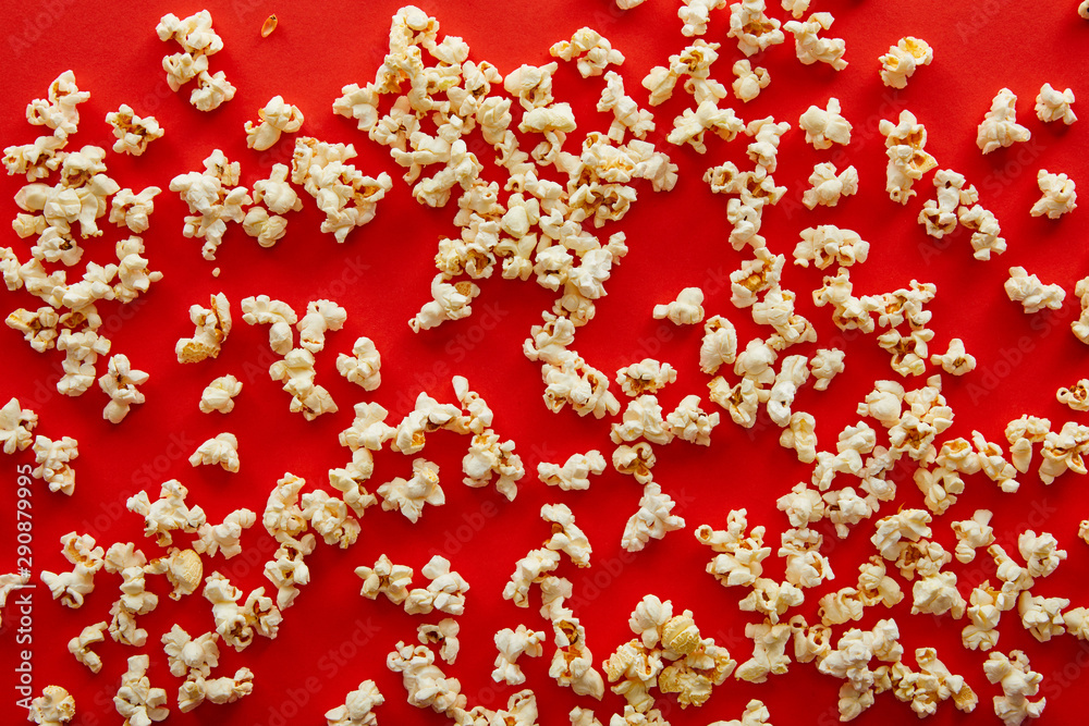 top view of fresh popcorn scattered on red background
