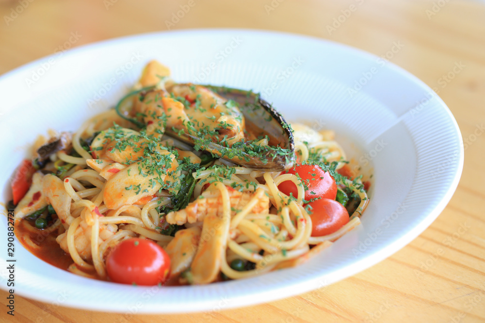 Seafood aaspicy spagetti with scallop, squid, shrimp and basil in white plate.  The famous Italian dish used long slim noodle.