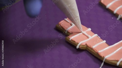 Woman making gingerbread house. garnishes with white cream