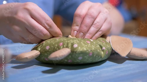 woman sews a rag doll with her hands