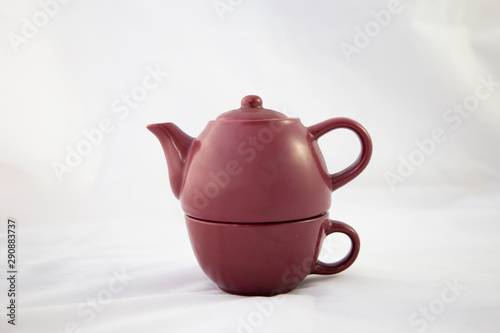 Tetera color granate de ceramica sobre fondo blanco. Vista individual. Recortar. Está dividida en dos partes porque es una tetera individual que tiene el vaso para tomar el té en la parte de abajo. Se photo
