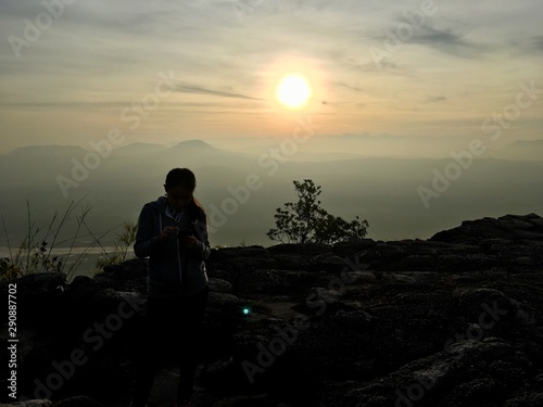 Woman standing on the cliff mountain, sunset background