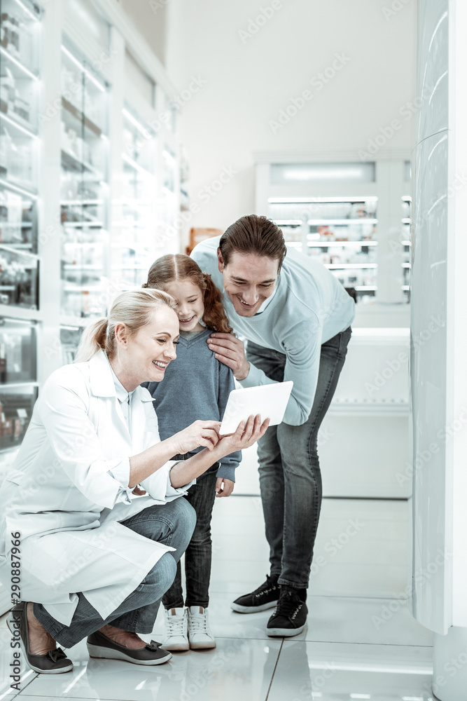 Obraz premium Pharmacy employee pointing at the tablet to man and kid