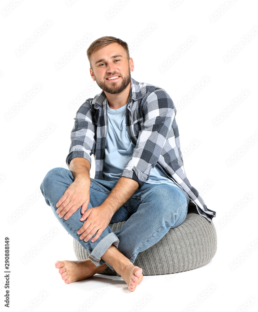 Handsome young man sitting on pouf against white background Handsome young man sitting on pouf against white background