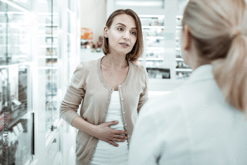 Attractive woman complaining to the druggist of her stomach ache. Attractive woman complaining to the druggist of her stomach ache.