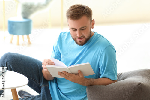 Handsome young man reading book at home