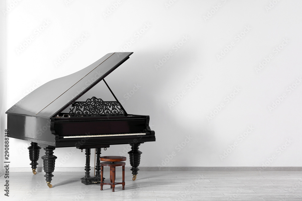 Black grand piano near white wall in empty room Stock Photo | Adobe Stock