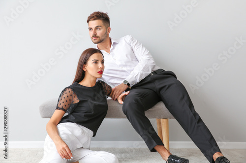 Stylish young couple near white wall