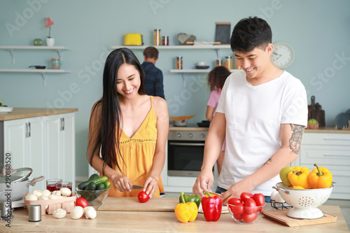 Happy Asian couple cooking together in kitchen