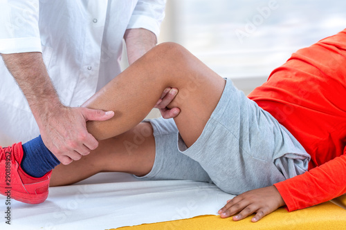 Doctor examining boy leg because of knee problem symptomset hospital photo