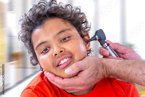 Ear examination. Paediatrician using an otoscope to examine a young boy's ear. the hospital